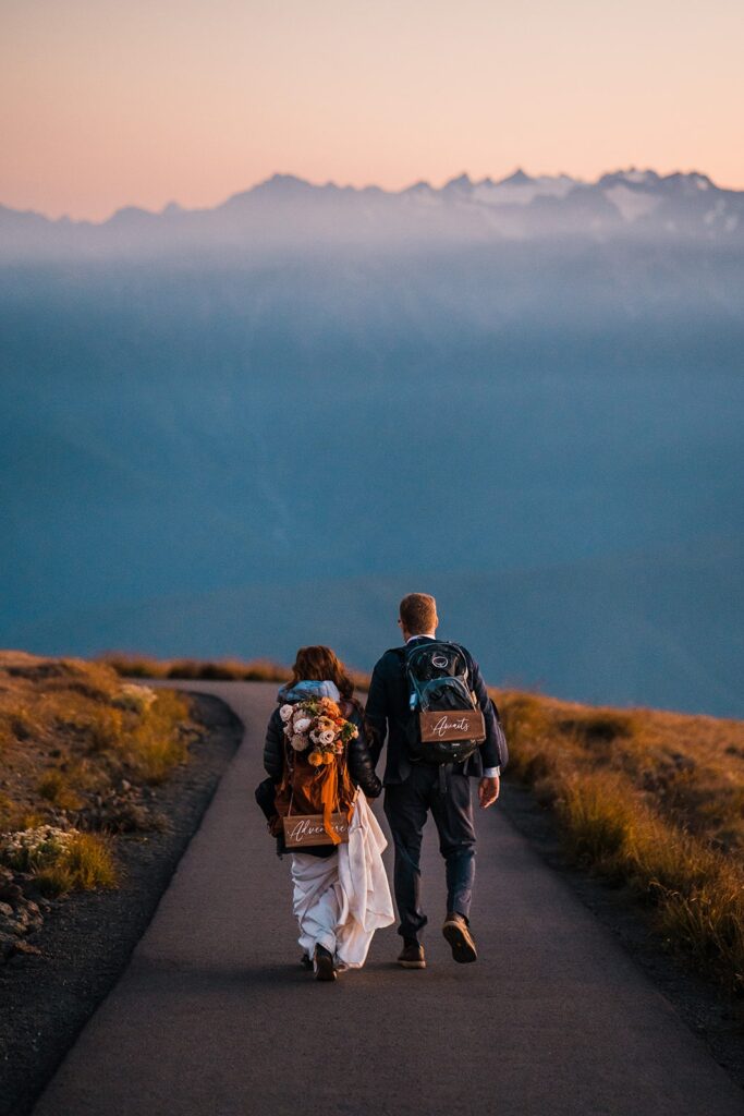 Bride and groom hold hands while they hike down the mountain after eloping in Olympic National Park