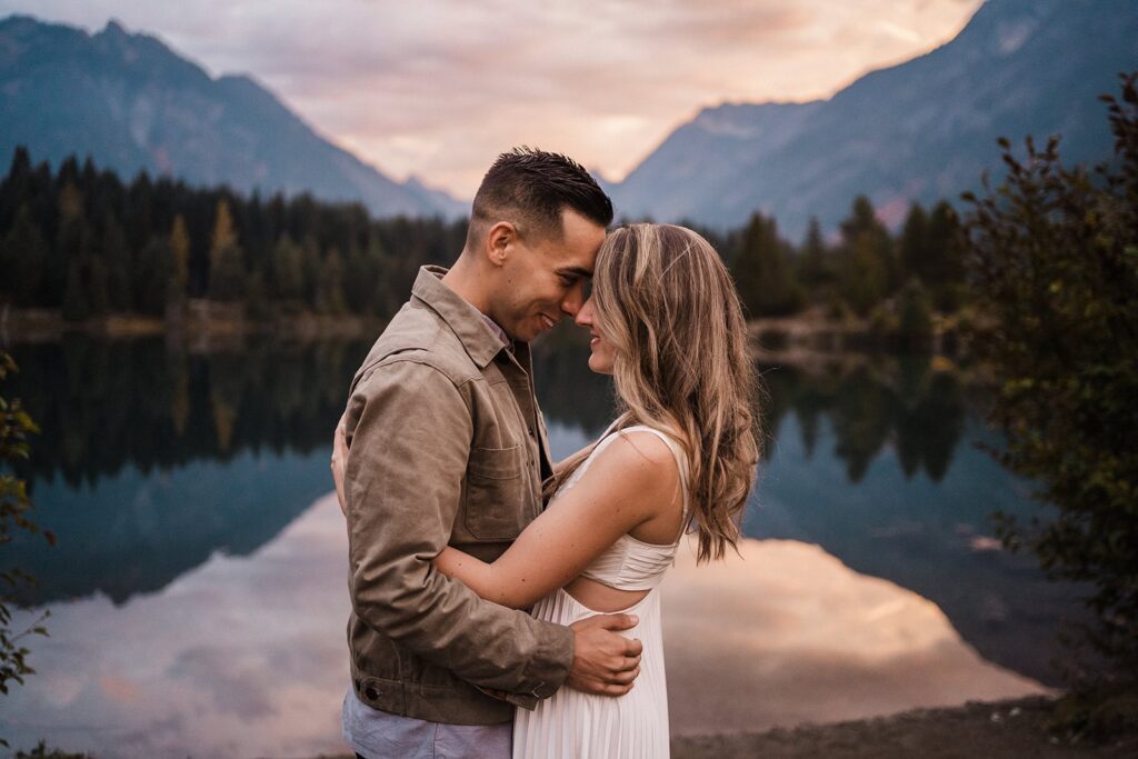 Bride and groom hug by a scenic lake during their sunrise adventure session in the PNW