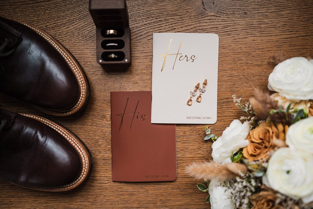 Leather hiking boots and white elopement flowers with white and rust colored vow books