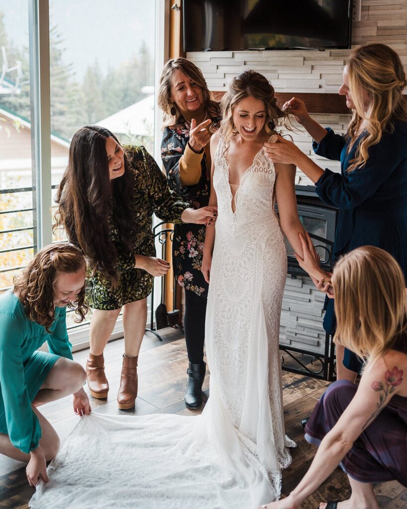 Family and friends help bride into her wedding dress during her pacific northwest elopement