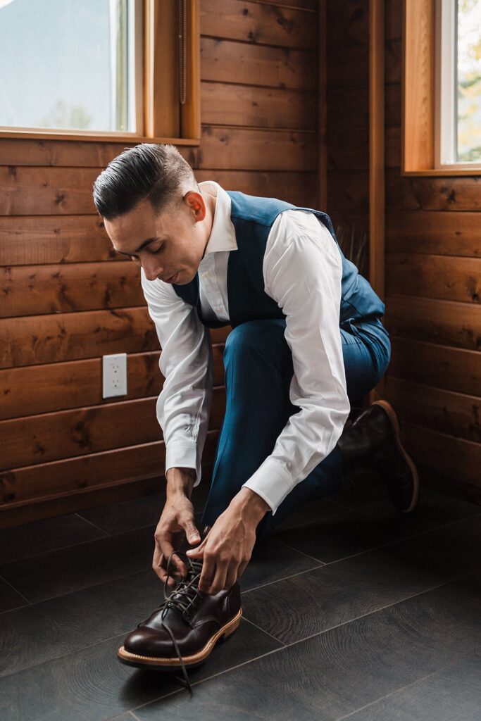 Groom putting on his leather shoes while getting ready for his pacific northwest elopement