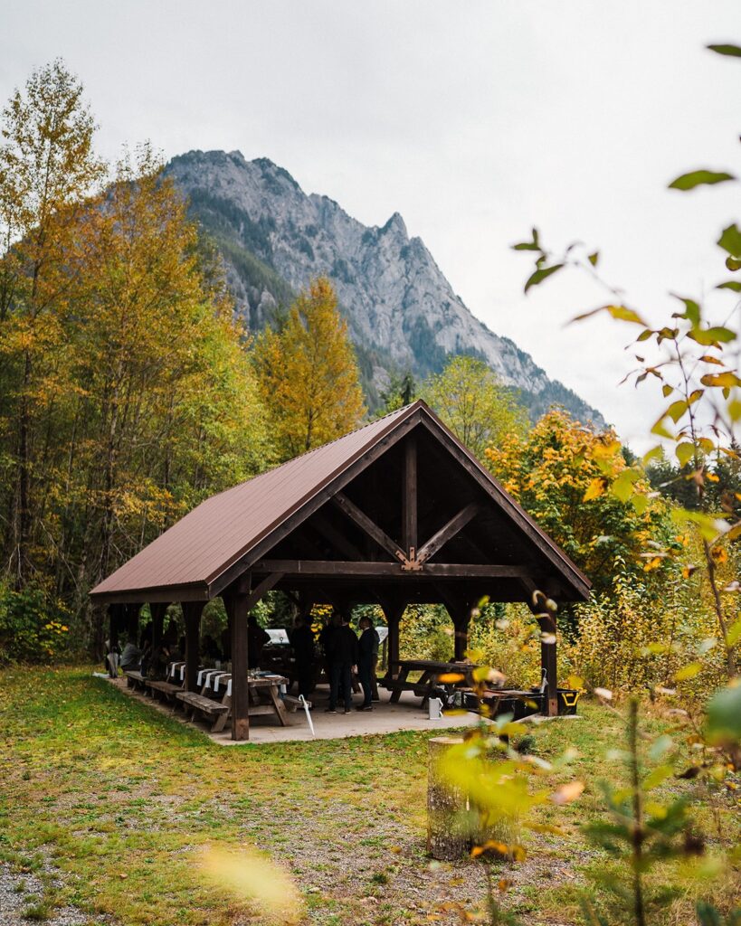 Guests sit in a covered pavilion at a Pacific Northwest elopement in Snoqualmie