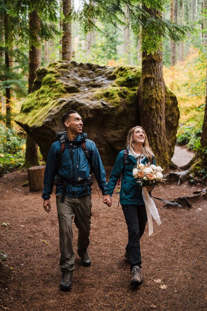 Bride and groom hold hands while hiking through the forest during their elopement in Snoqualmie