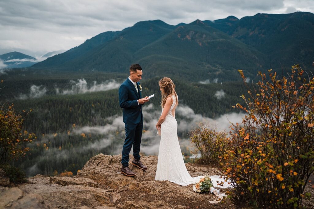 Groom reads vows to bride during their foggy Pacific Northwest elopement in Snoqualmie