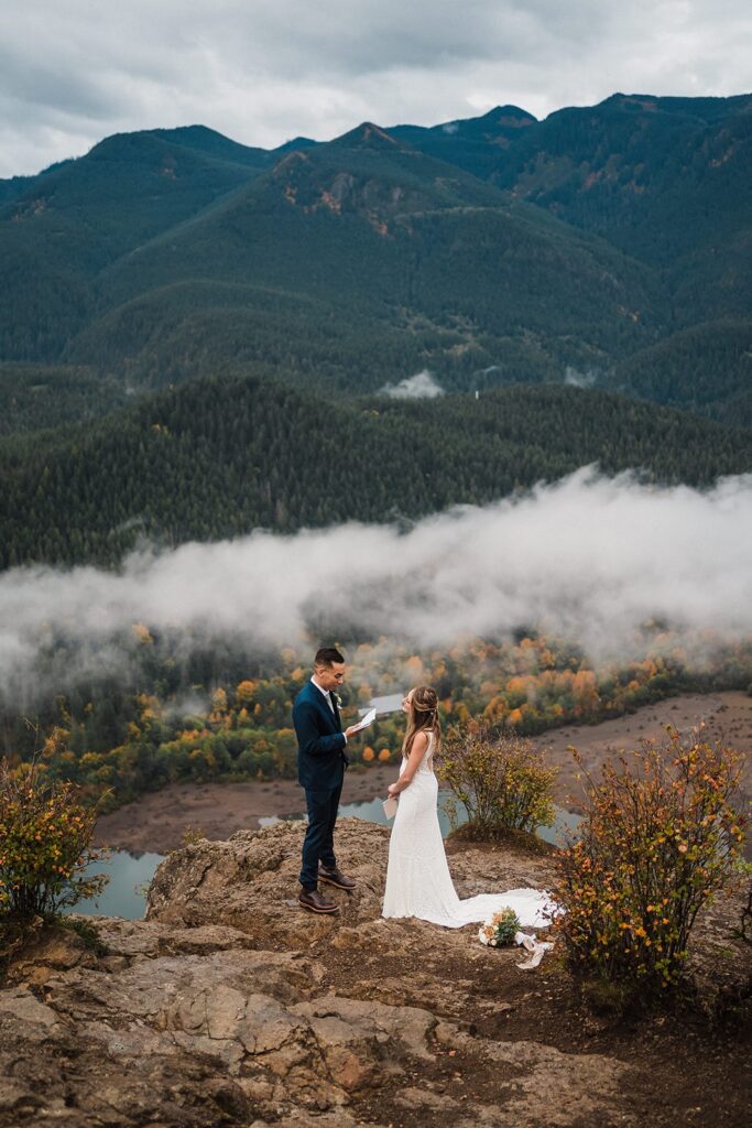 Groom reads vows to bride during their foggy Pacific Northwest elopement in Snoqualmie