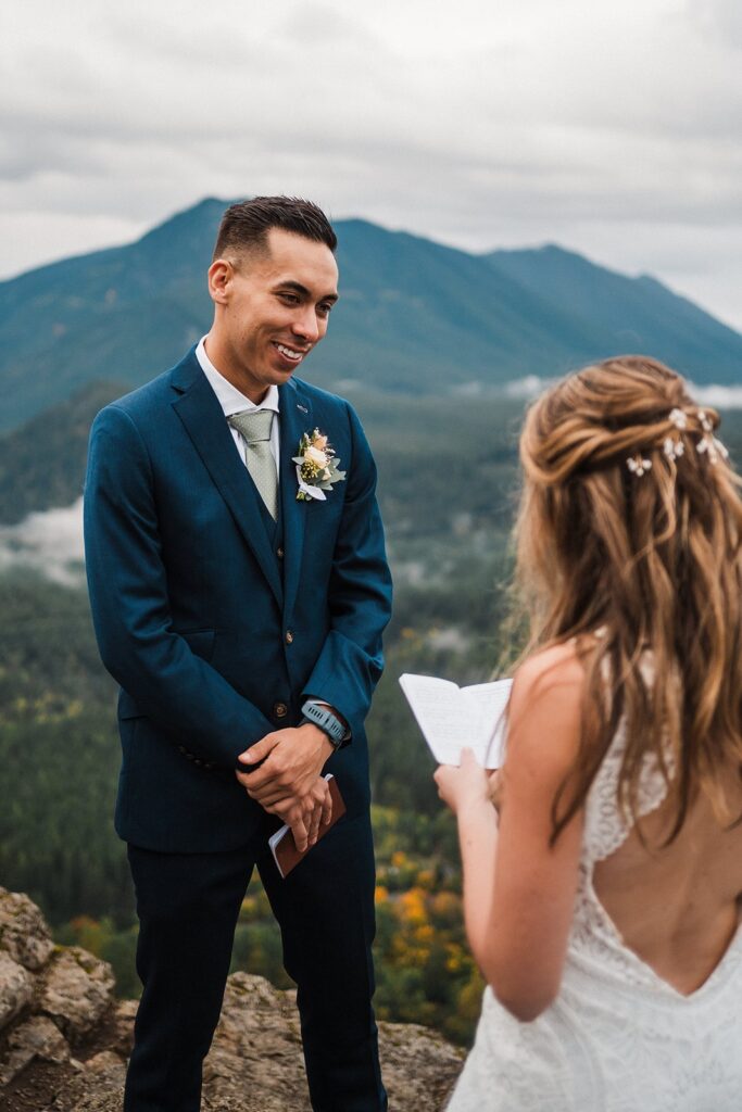 Groom smiles while bride reads private vows during their Pacific Northwest elopement