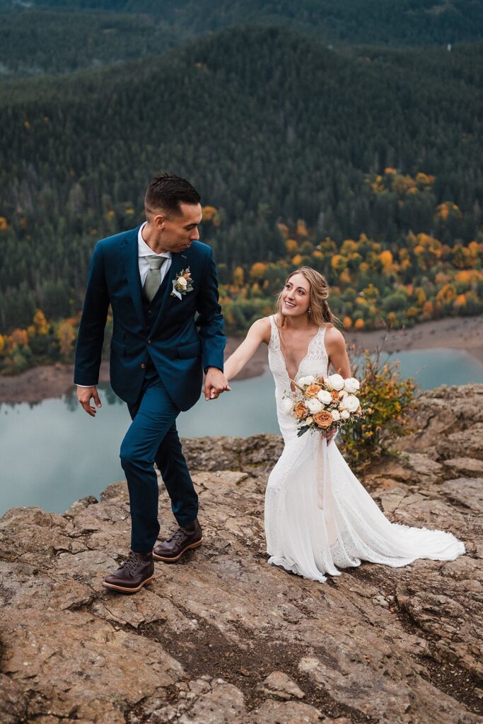 Bride and groom hold hands while hiking up a mountain trail during their elopement in Snoqualmie