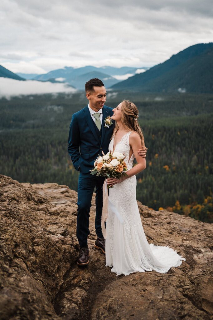 Bride and groom hug at the top of a mountain overlook during their elopement in Snoqualmie