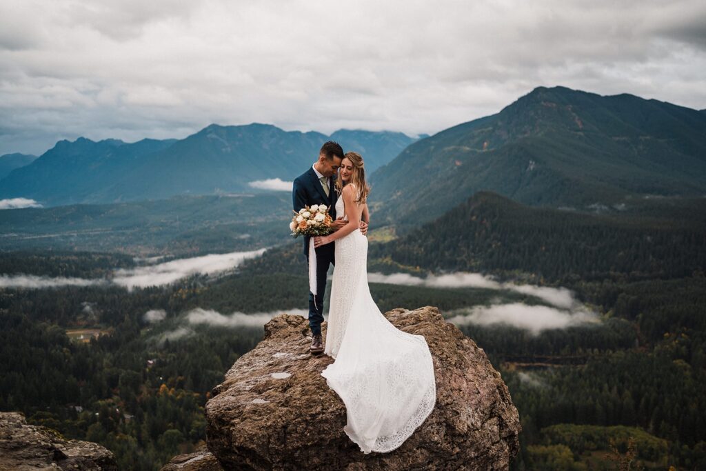 Bride and groom stand on top of a mountain overlook during their Pacific Northwest elopement