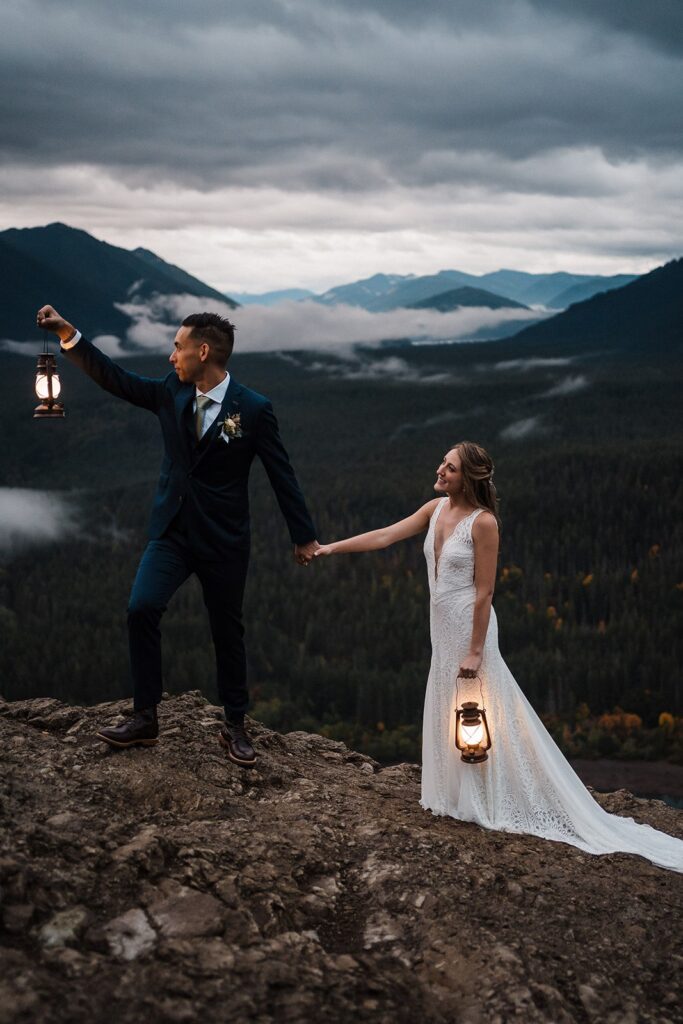 Bride and groom hold lanterns while hiking up a mountain at their elopement in Snoqualmie