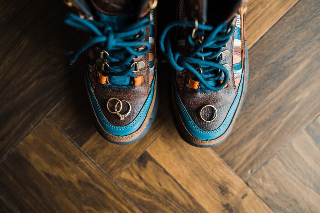 Wedding bands sitting on top of elopement hiking boots with blue laces