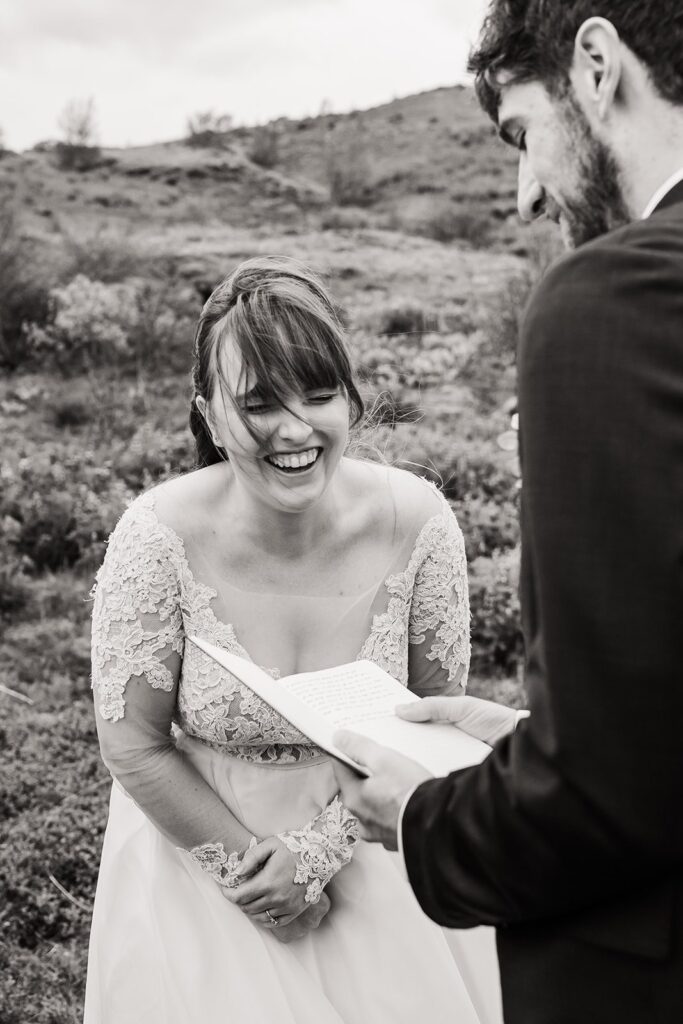 Bride laughs while groom reads vows during their outdoor elopement ceremony in Iceland