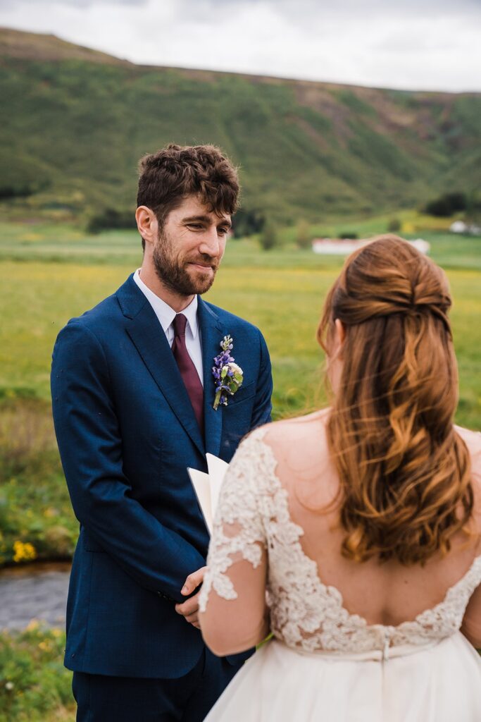 Groom smiles while bride reads elopement vows during their Iceland elopement