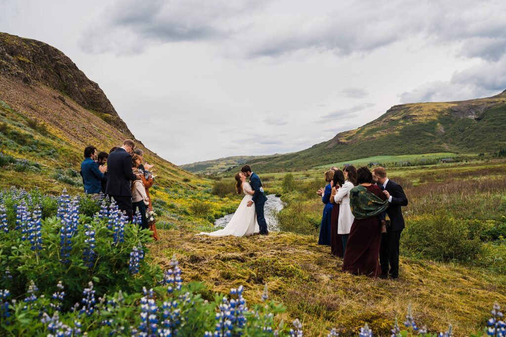 Bride and groom kiss during their elopement ceremony in a lupine field in Iceland