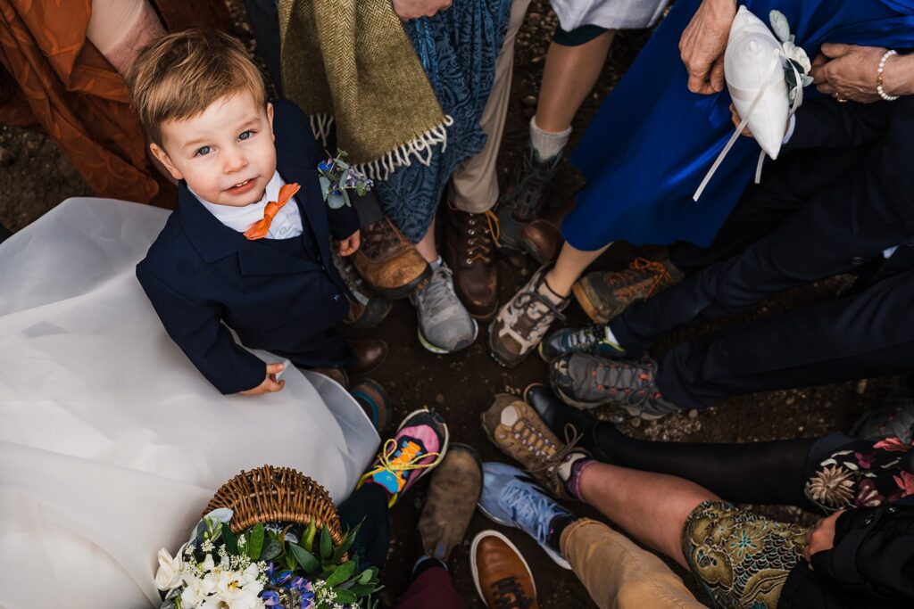 Little boy looks up at the camera while guests put all their hiking shoes together in a circle