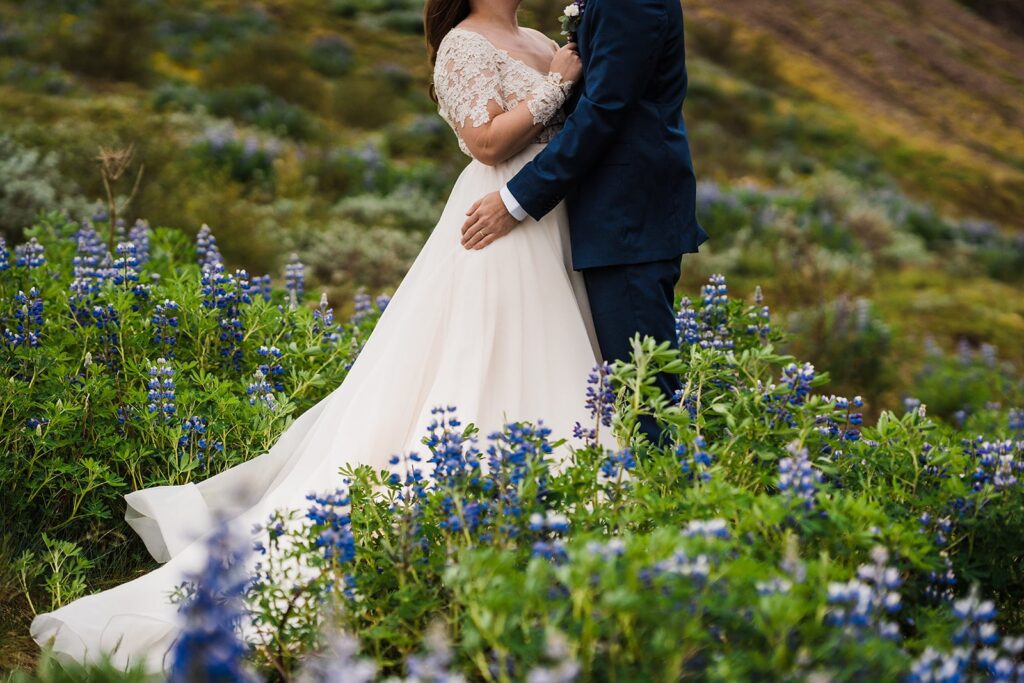 Bride and groom stand in the middle of a lupine wildflower field in Iceland for their elopement portraits