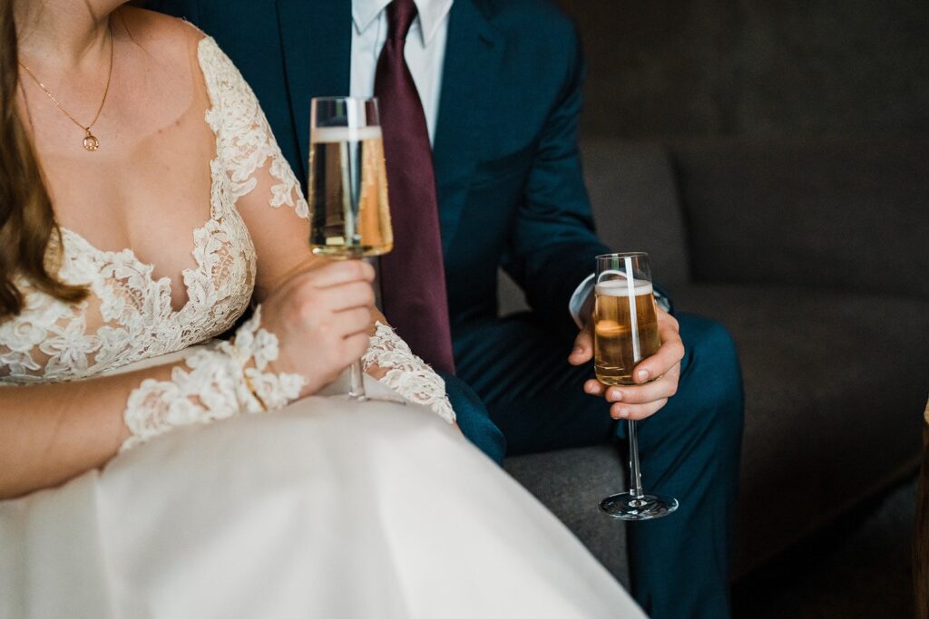 Bride and groom hold champagne flutes at their celebratory meal in Iceland