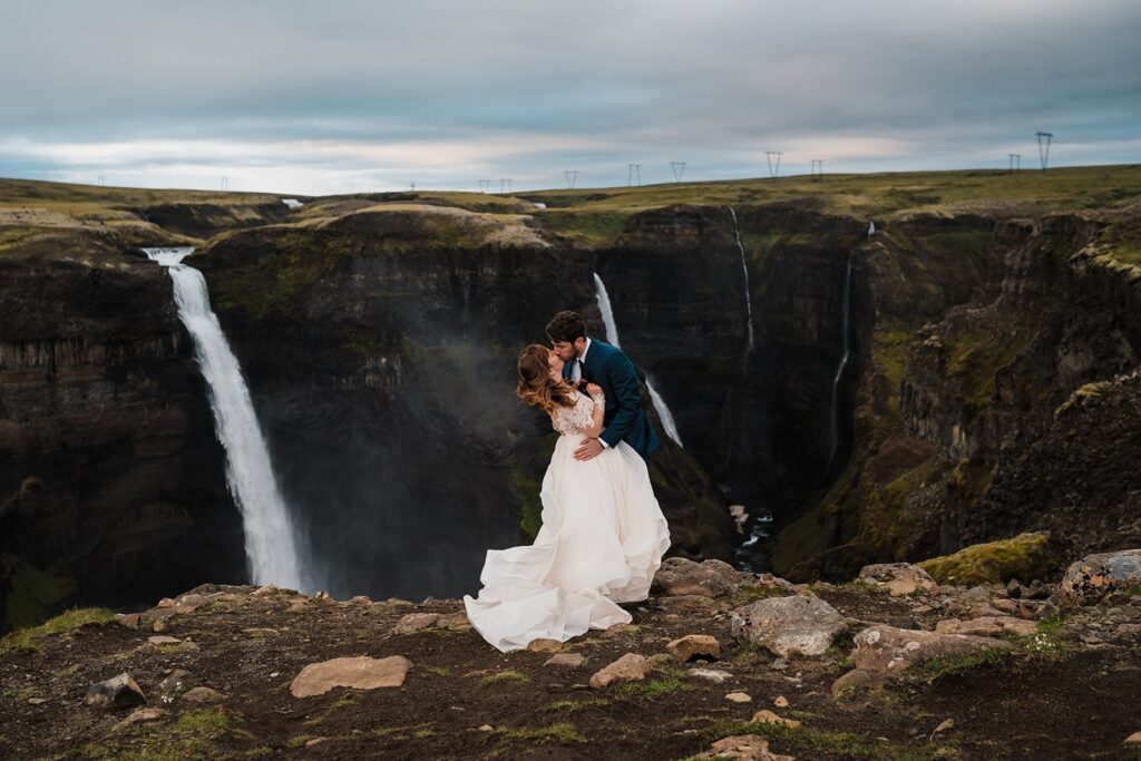 Bride and groom kiss at the top of a waterfall overlook during their Iceland elopement