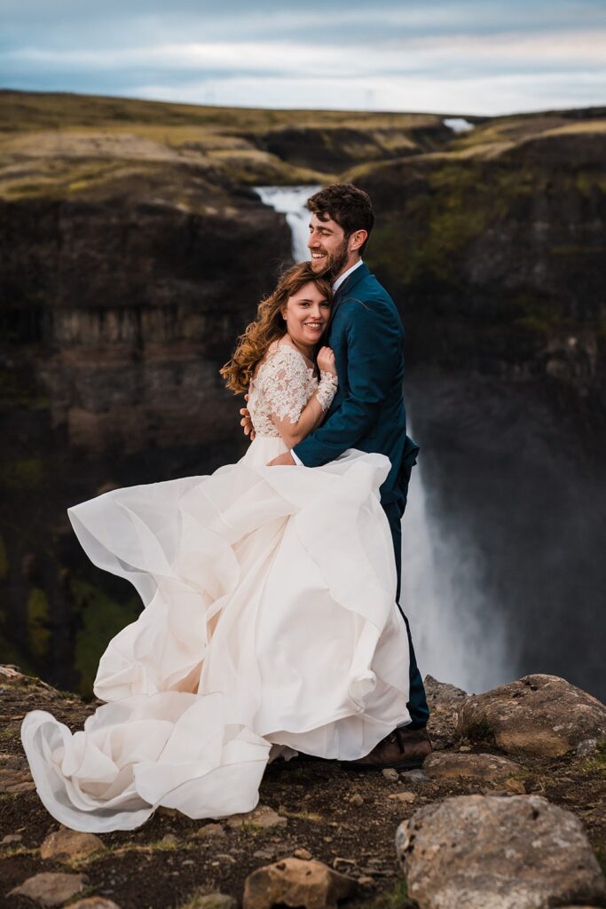 Bride and groom hug during their elopement photos in front of a waterfall in Iceland 