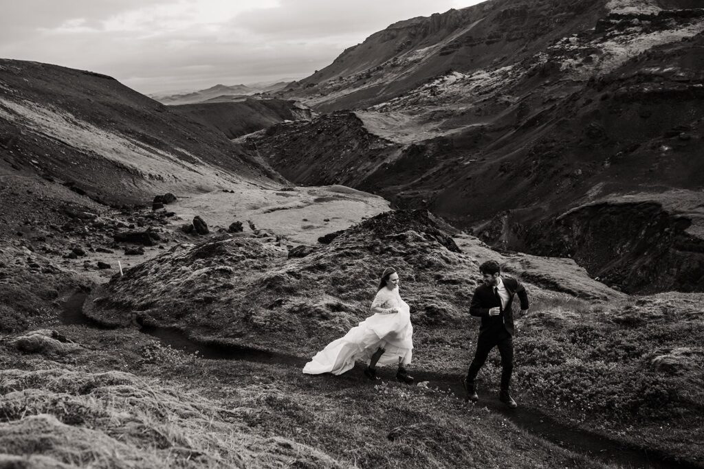 Bride and groom run along a hiking trail during their adventure elopement