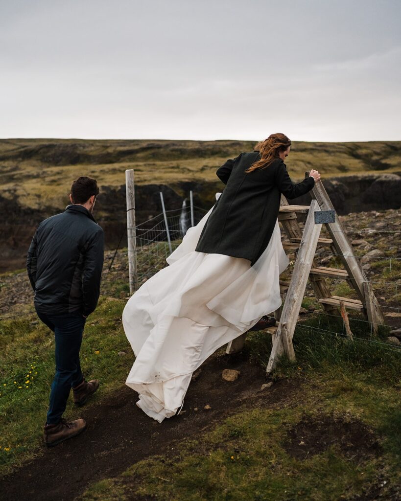 Brides climbs over a barbed wire fence while hiking for her adventure elopement