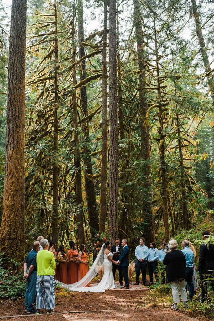 Bride and groom hold hands during their micro wedding in the forest
