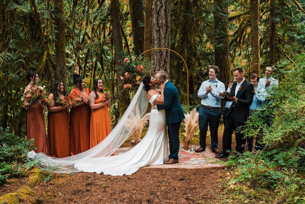 Bride and groom kiss in the forest after exchanging wedding vows at their micro wedding