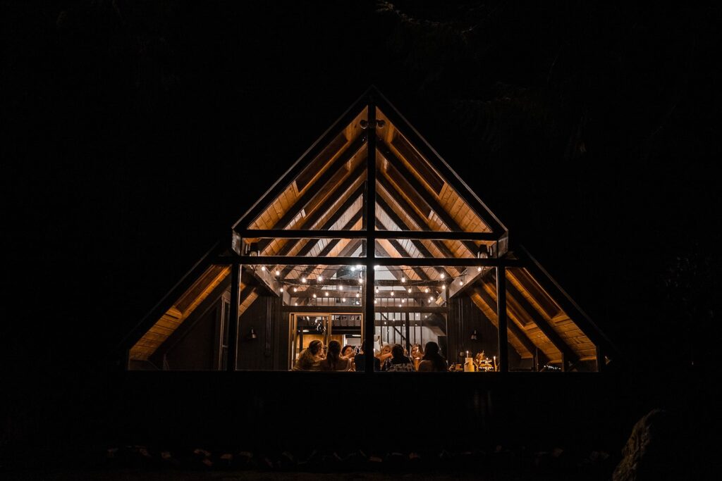 Guests enjoy a celebratory meal in an a-frame micro wedding venue cabin