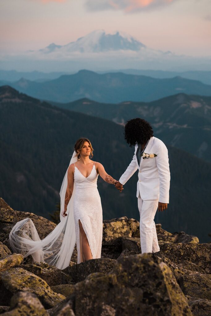 Bride and groom hold hands while walking along a mountain trail during their elopement in Snoqualmie
