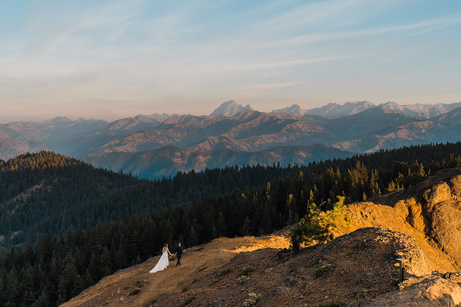 Bride and groom hold hands while hiking through the mountain trails during their elopement in Washington