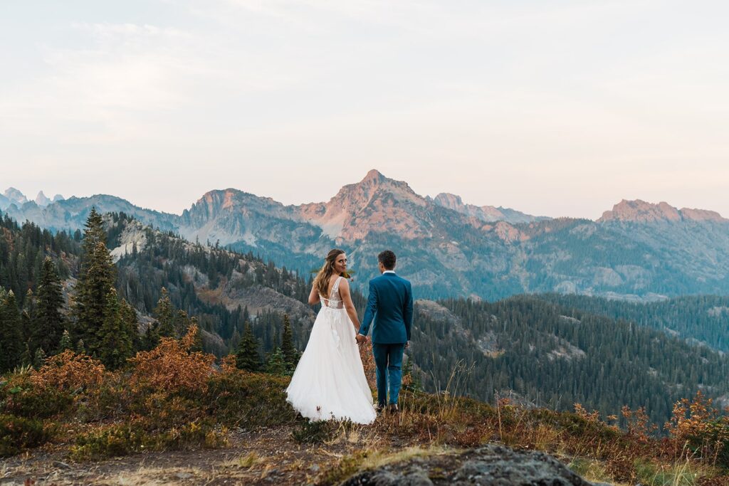 Bride and groom hold hands while exploring a mountain trail in Snoqualmie