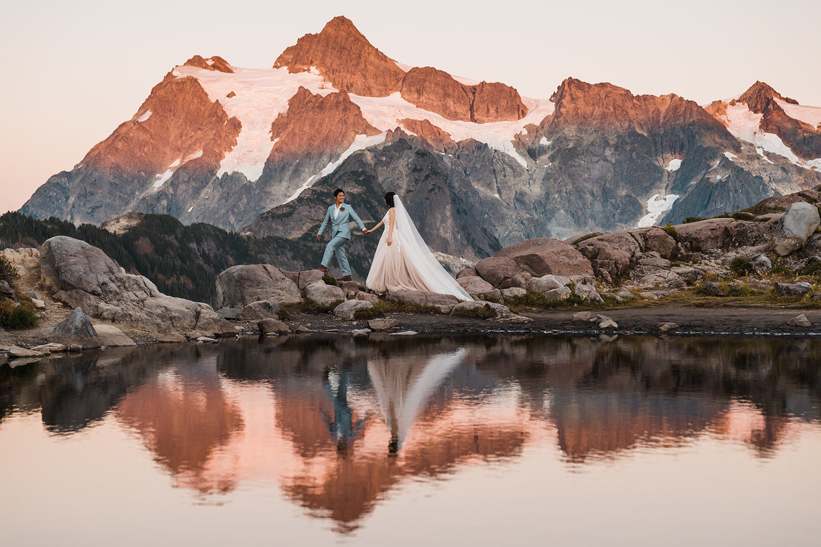 Bride and groom hold hands as they walk along a mountain trail at their national park wedding in the national forest 