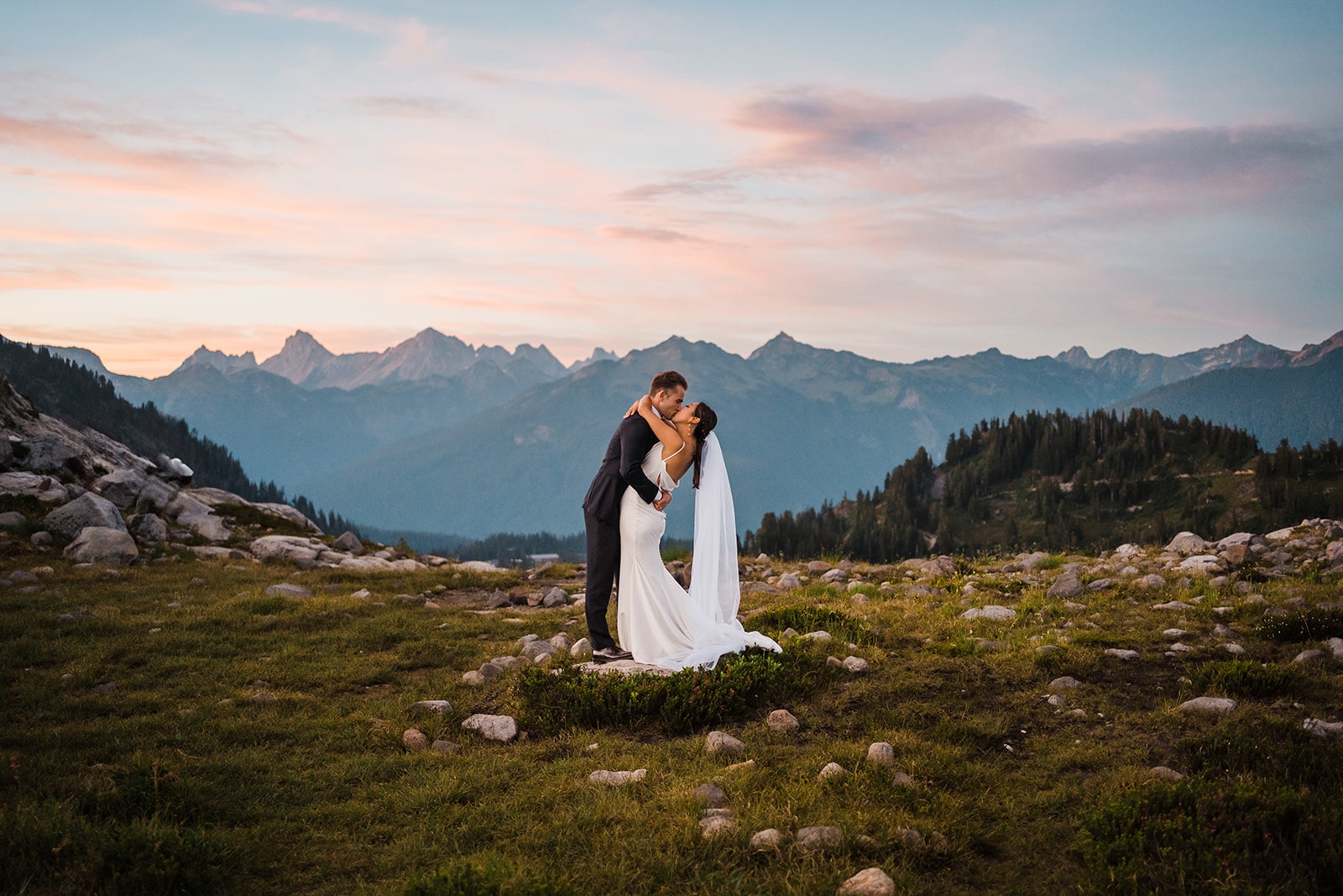 Bride and groom kiss on a mountain trail during their national park wedding in Washington