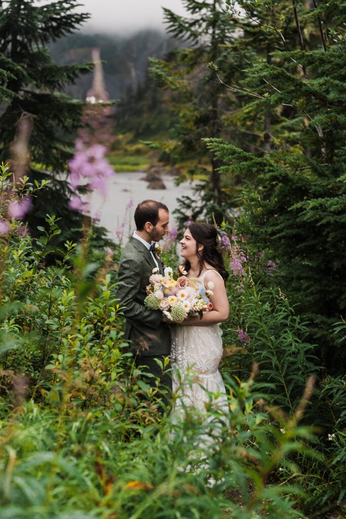 Bride and groom standing on a green mountain trail during their rainy wedding in the North Cascades