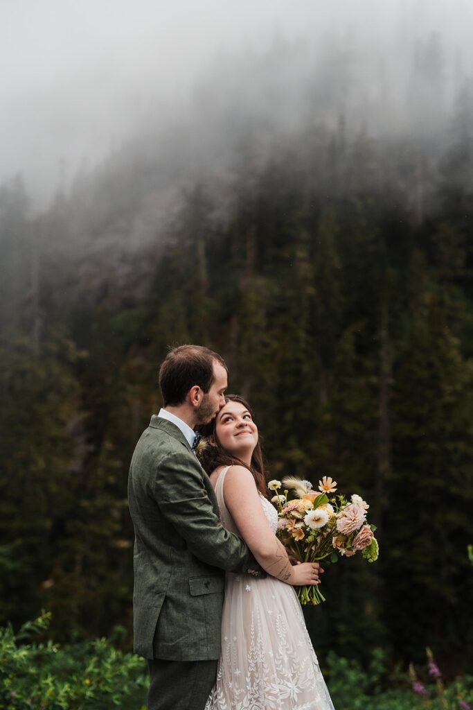 Bride and groom hug during their rainy wedding photos in the North Cascades