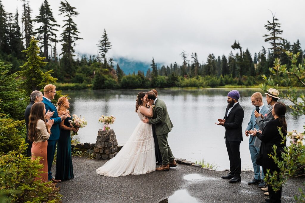 Bride and groom kiss during their North Cascades wedding ceremony in the rain