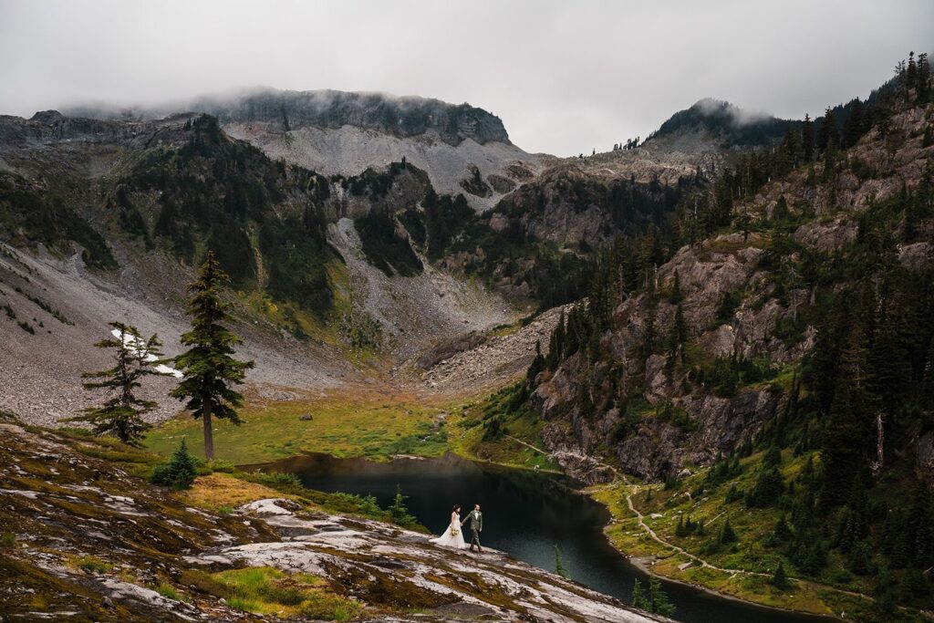 Bride and groom hike a trail in the North Cascades during their rainy wedding photos