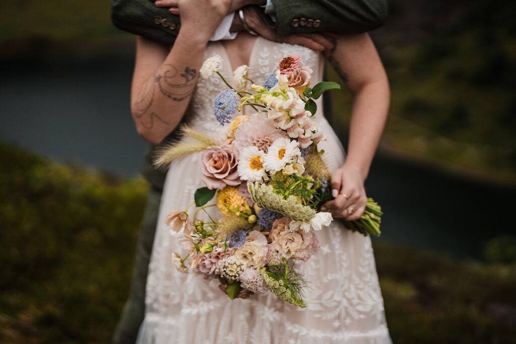 Bride holds a pastel, white, and green wedding flower bouquet during her North Cascades wedding