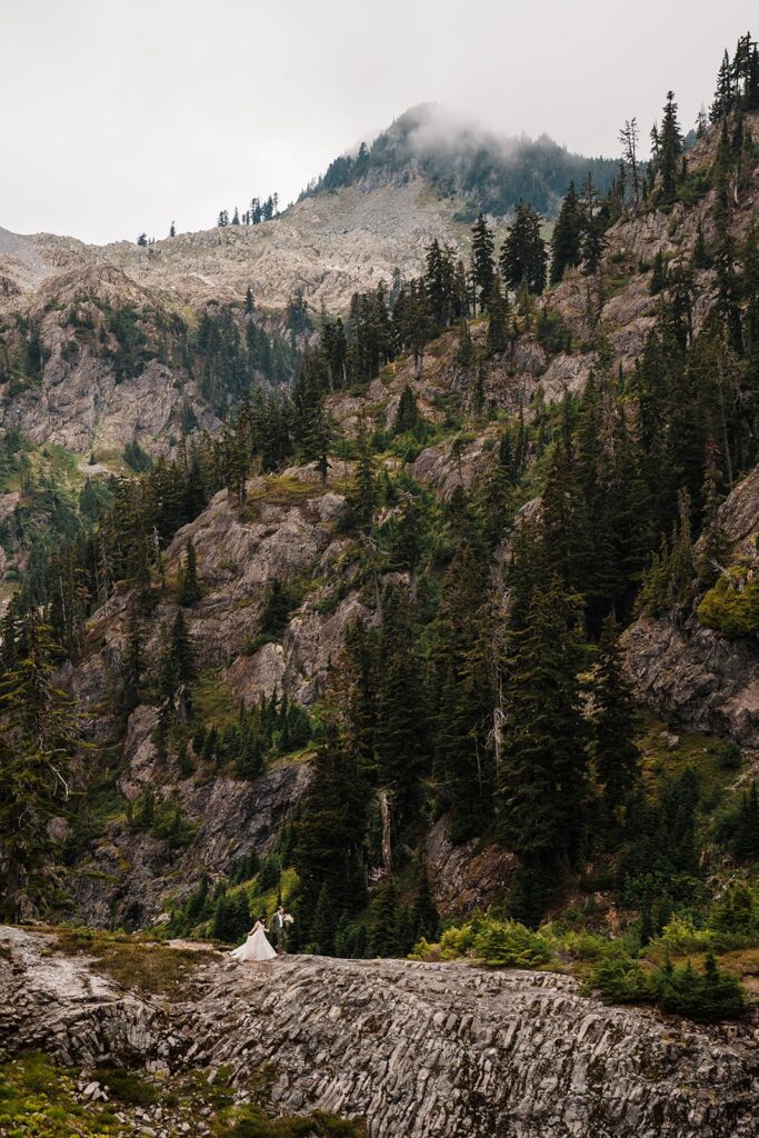 Bride and groom hike on a North Cascades mountain trail during their rainy wedding