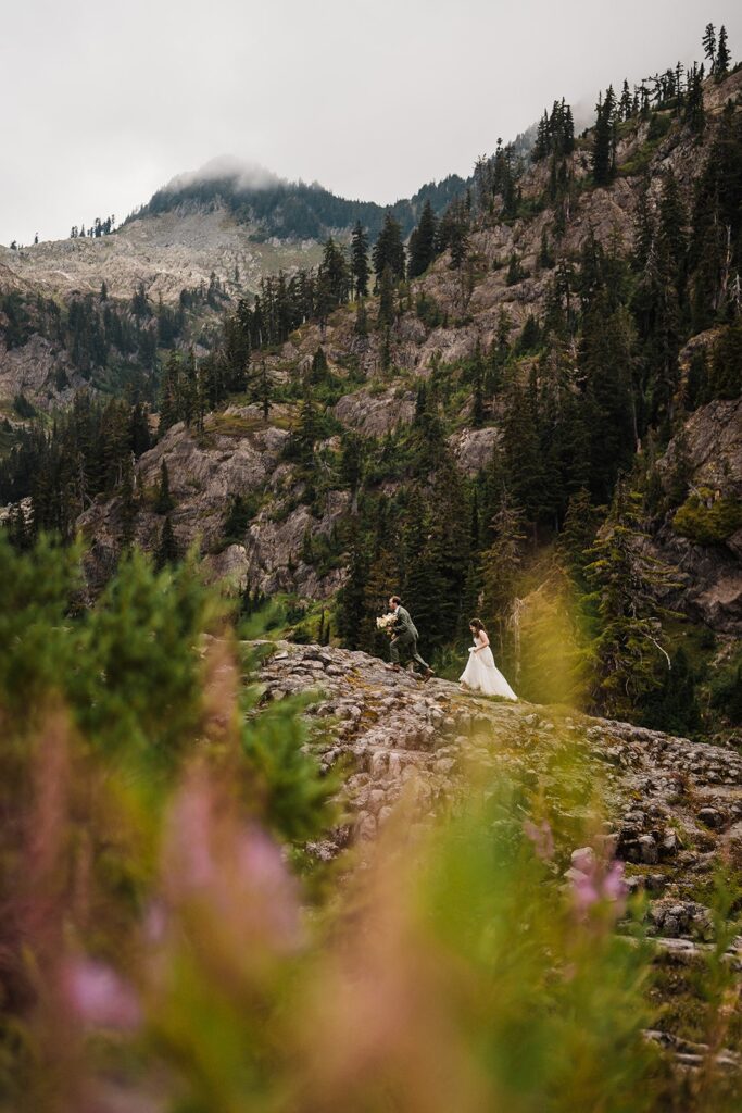 Bride and groom hike on a North Cascades mountain trail during their rainy wedding