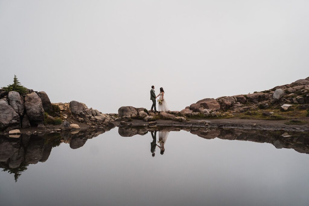 Bride and groom hold hands at Artist Point during their rainy North Cascades wedding