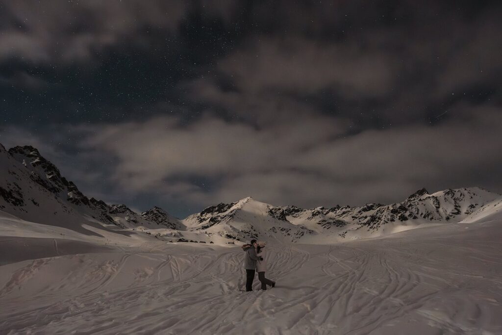 Couple kisses in the snow during Alaska astrophotography