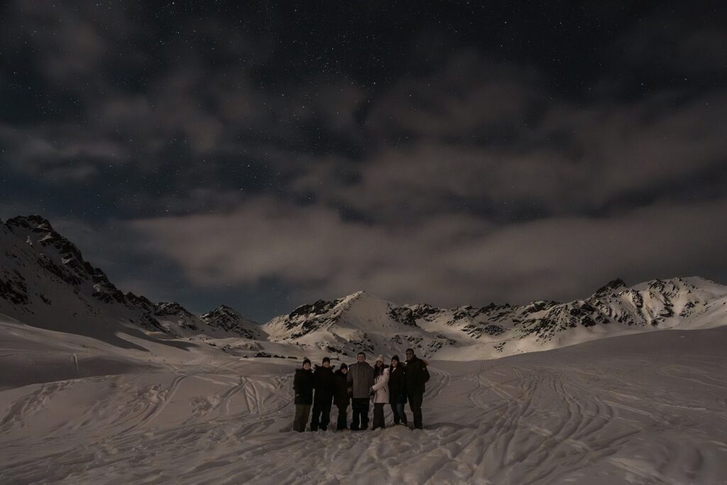 Family stands in the snow during Alaska astrophotography 