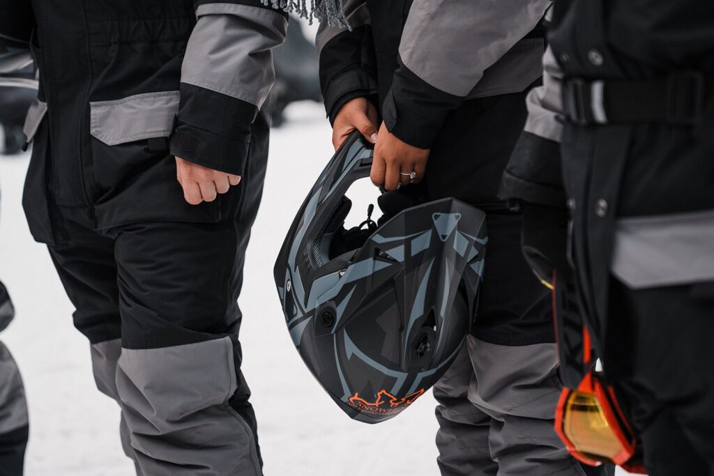 Woman holds a helmet while getting to ride a snowmobile during her Alaska elopement