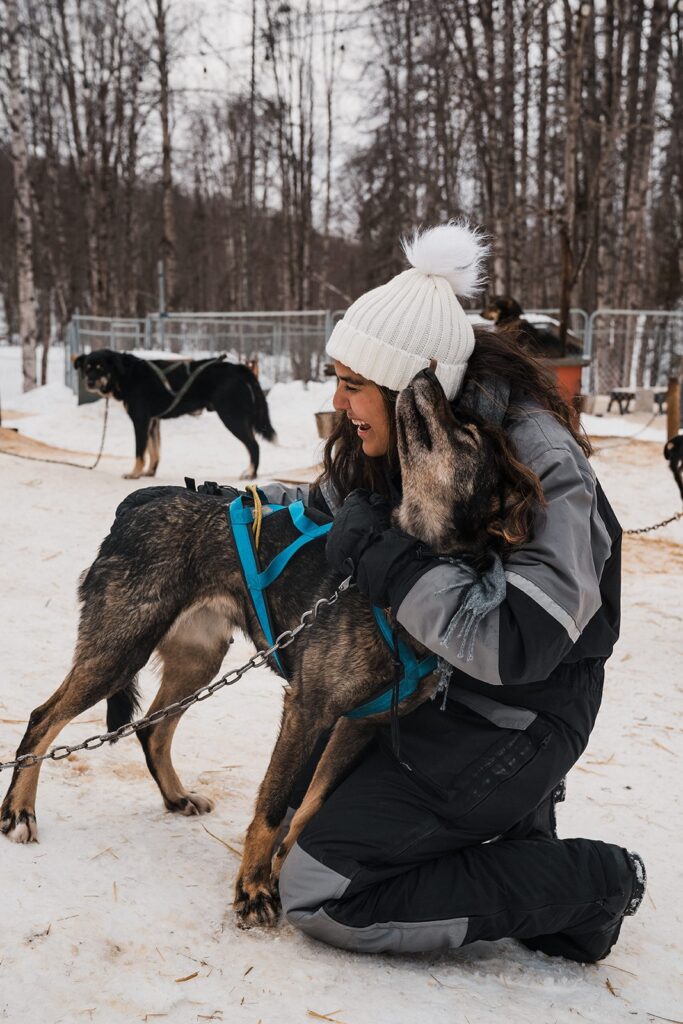 Woman hugs a dug during her dog-sledding elopement in Alaska