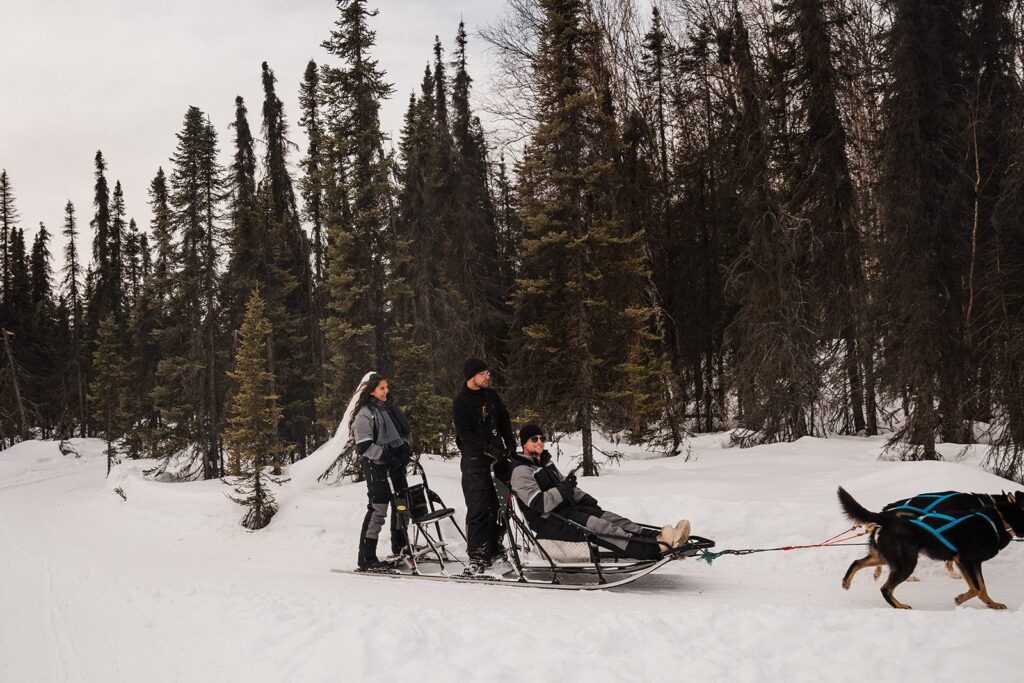 Couple rides on a dog sled during their adventure elopement in Alaska