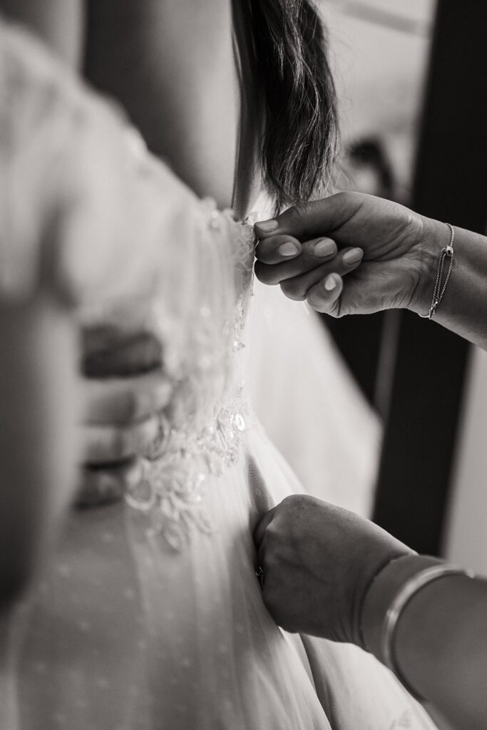 Mother helps bride zip up her dress for her glacier elopement in Alaska