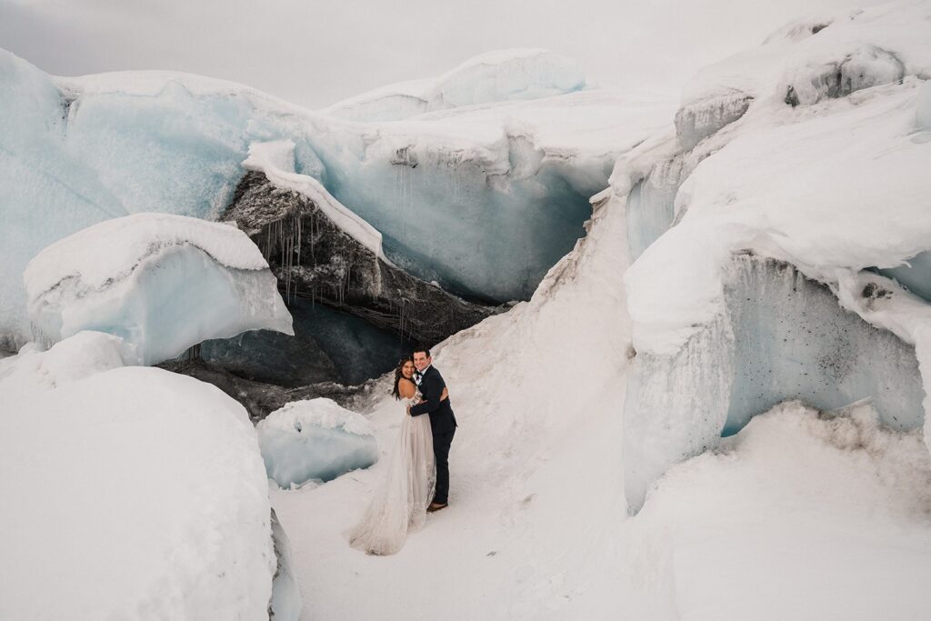 Bride and groom hug during their Alaska glacier elopement in the snow 