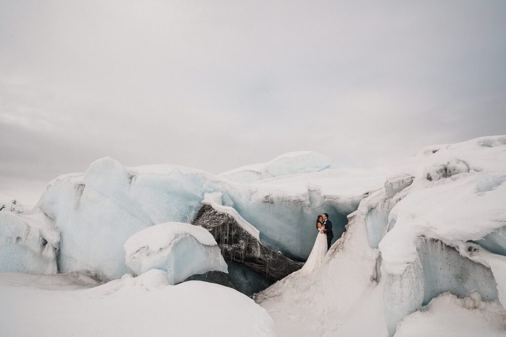 Bride and groom hug during their snowy glacier elopement in Alaska