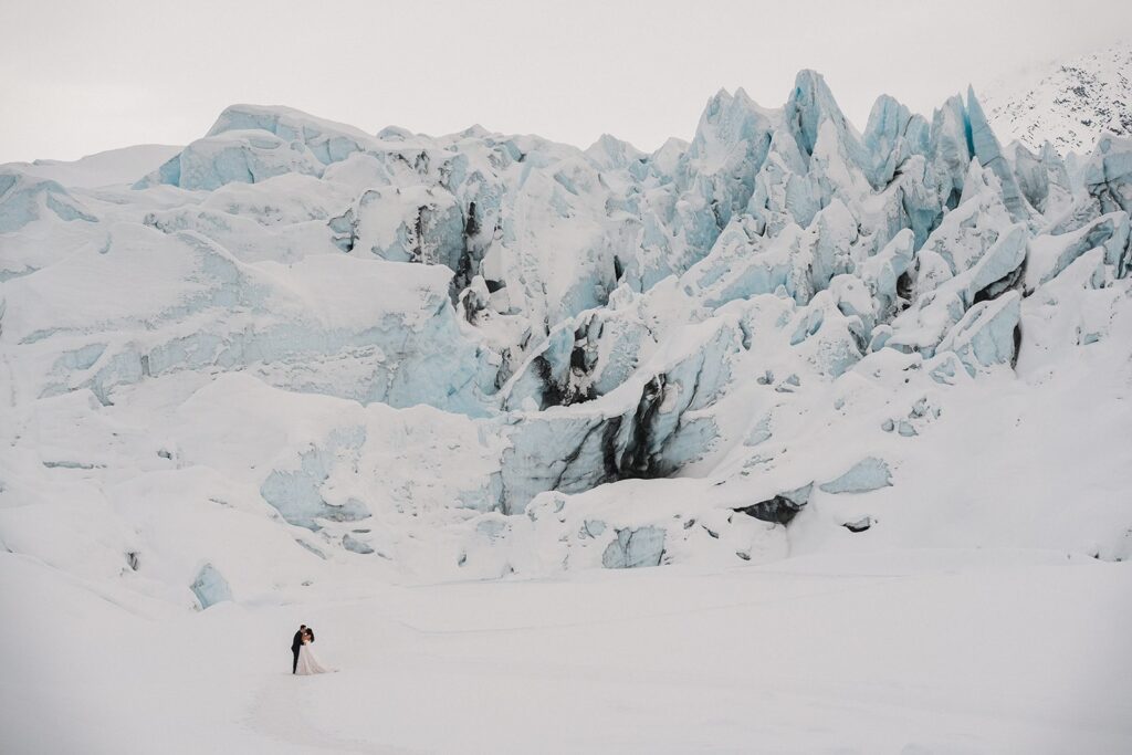 Bride and groom kiss on a snowy glacier in Alaska